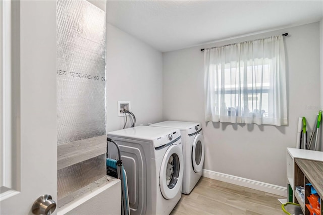 clothes washing area with light hardwood / wood-style flooring and washer and clothes dryer