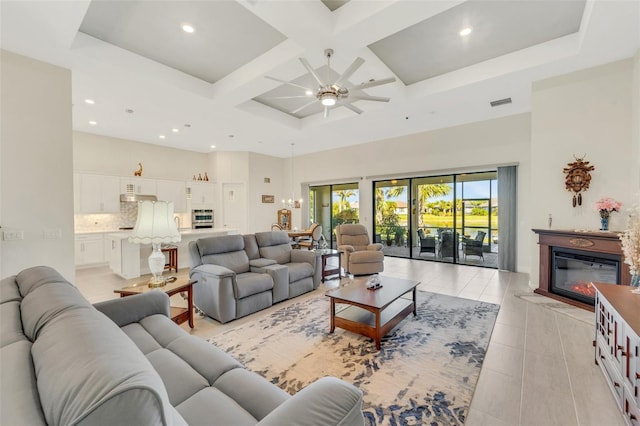 living room featuring light tile patterned floors, ceiling fan, beamed ceiling, a high ceiling, and coffered ceiling