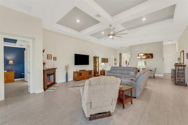 tiled living room featuring beam ceiling, coffered ceiling, and ceiling fan with notable chandelier