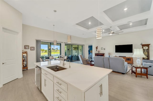 kitchen with sink, white cabinetry, coffered ceiling, decorative light fixtures, and a center island with sink