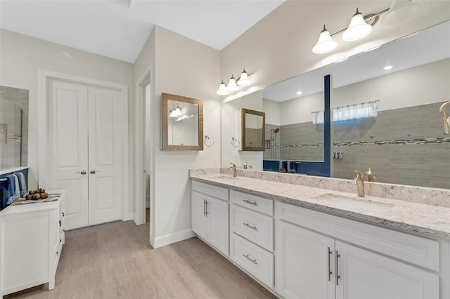 bathroom with vanity, tiled shower, and hardwood / wood-style floors