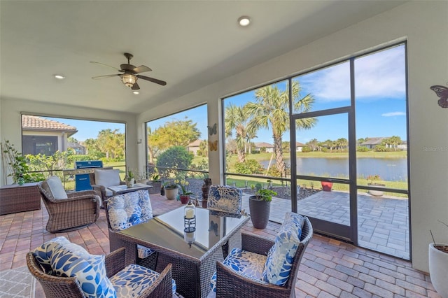 sunroom featuring a water view and ceiling fan