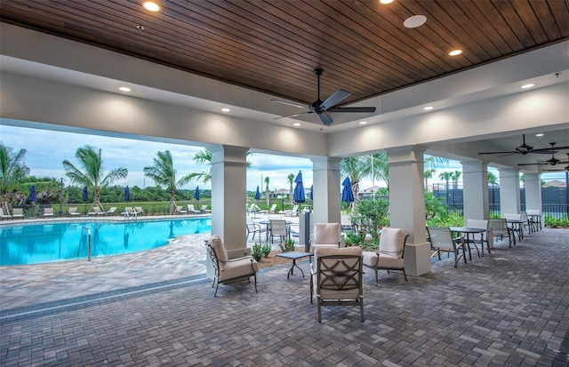 pool at dusk featuring a patio and ceiling fan