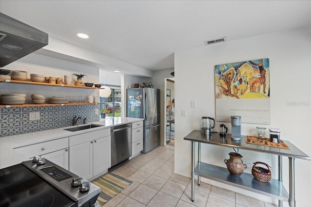 kitchen featuring sink, light tile patterned flooring, white cabinets, appliances with stainless steel finishes, and tasteful backsplash