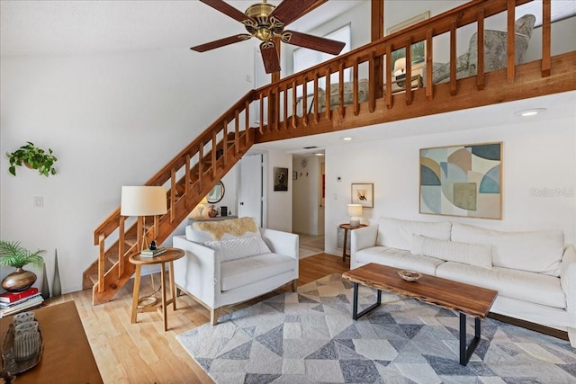 living room with a high ceiling, light hardwood / wood-style flooring, and ceiling fan