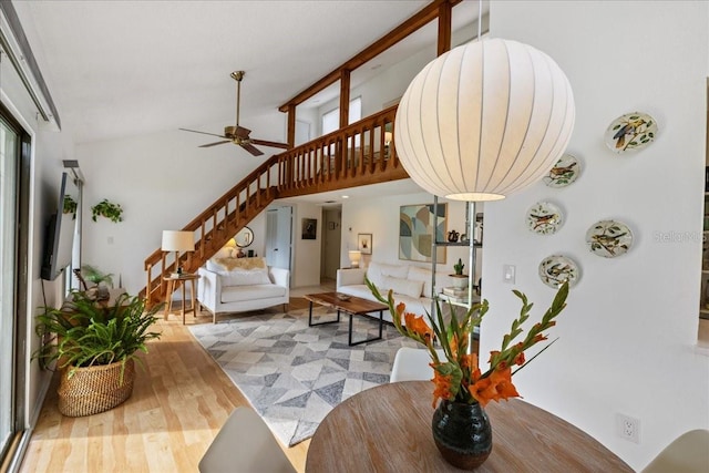 living room with ceiling fan, hardwood / wood-style flooring, and a high ceiling