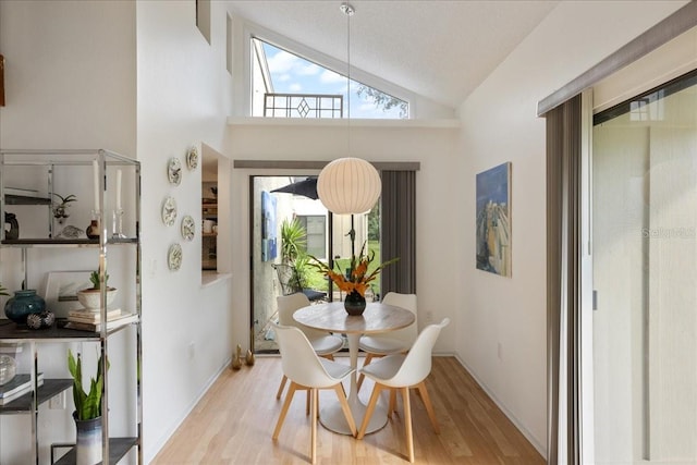 dining area with high vaulted ceiling and light wood-type flooring