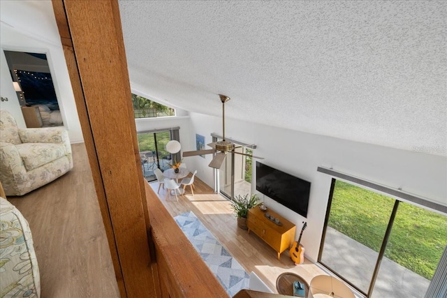 living room with lofted ceiling, light hardwood / wood-style flooring, a textured ceiling, and ceiling fan