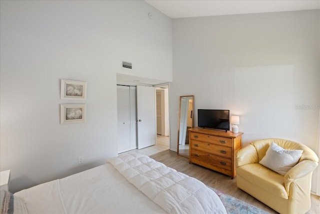 bedroom with light hardwood / wood-style flooring, a closet, and high vaulted ceiling