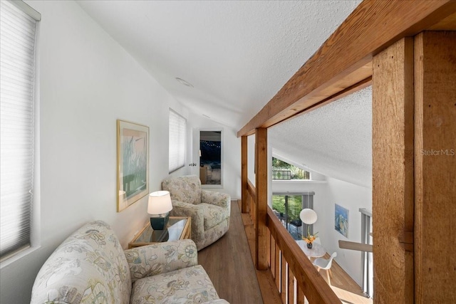 living room with hardwood / wood-style flooring, a textured ceiling, and vaulted ceiling