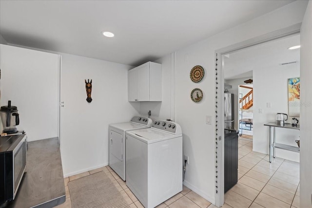 clothes washing area with cabinets, washer and dryer, and light tile patterned flooring