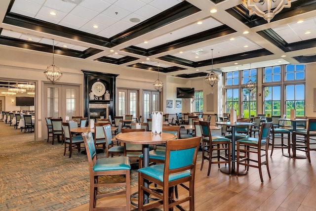 dining room featuring a high ceiling, coffered ceiling, hardwood / wood-style flooring, and beam ceiling