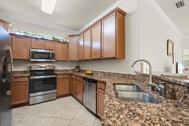 kitchen with stainless steel appliances, sink, crown molding, and dark stone countertops