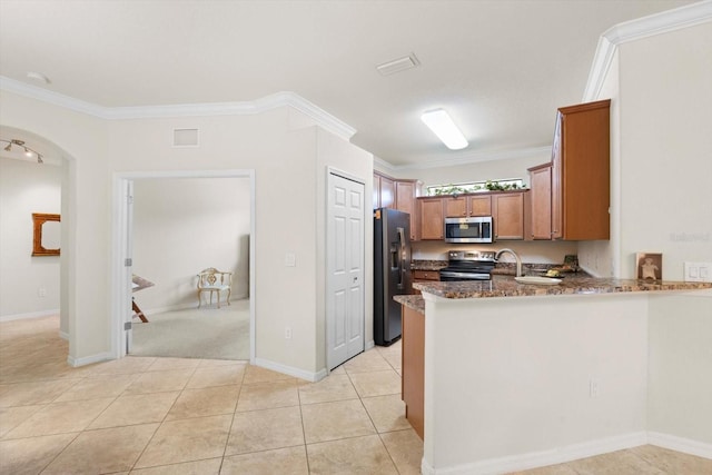 kitchen featuring stainless steel appliances, light tile patterned flooring, kitchen peninsula, ornamental molding, and dark stone counters