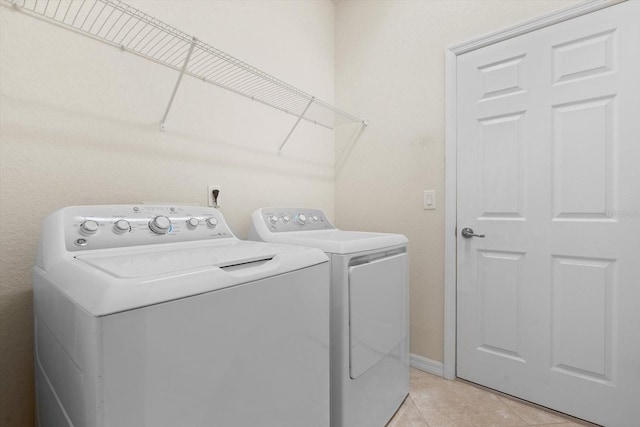 clothes washing area with washer and dryer and light tile patterned floors