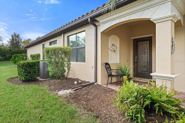 entrance to property featuring cooling unit and a yard