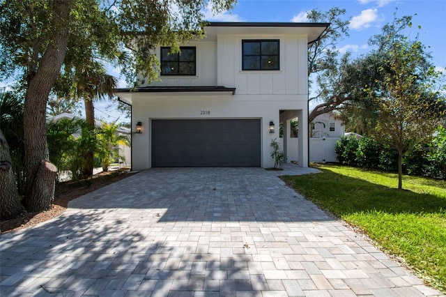 view of front of property with an attached garage, stucco siding, decorative driveway, and a front yard