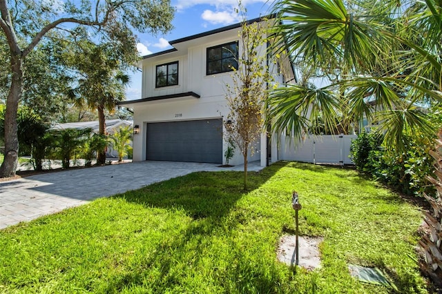 view of front of house featuring decorative driveway, a garage, stucco siding, and a front yard