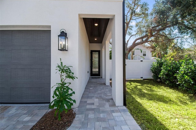 entrance to property with stucco siding, a yard, and fence