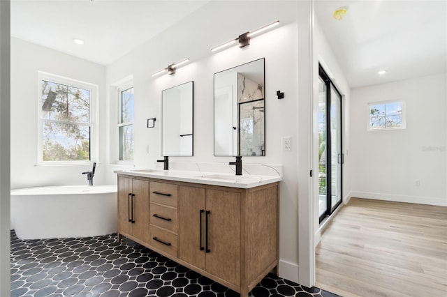 bathroom with double vanity, a stall shower, a sink, a soaking tub, and recessed lighting