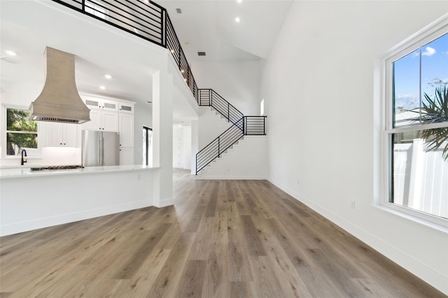 unfurnished living room featuring hardwood / wood-style flooring, high vaulted ceiling, and a healthy amount of sunlight