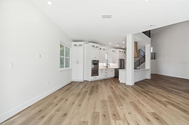 unfurnished living room featuring sink and light wood-type flooring