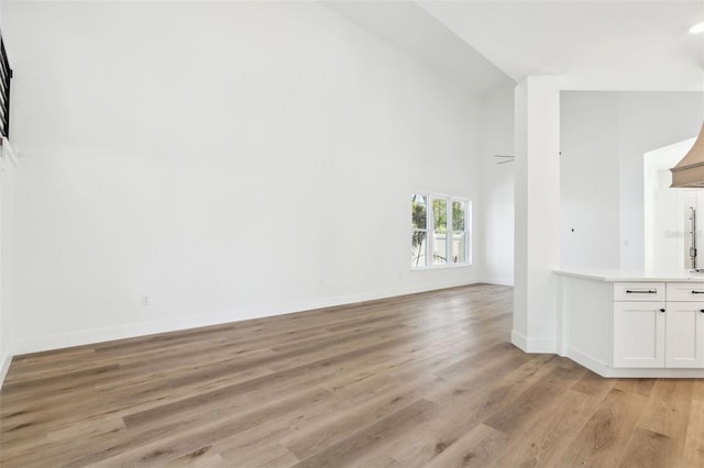 unfurnished living room featuring light wood-type flooring and high vaulted ceiling