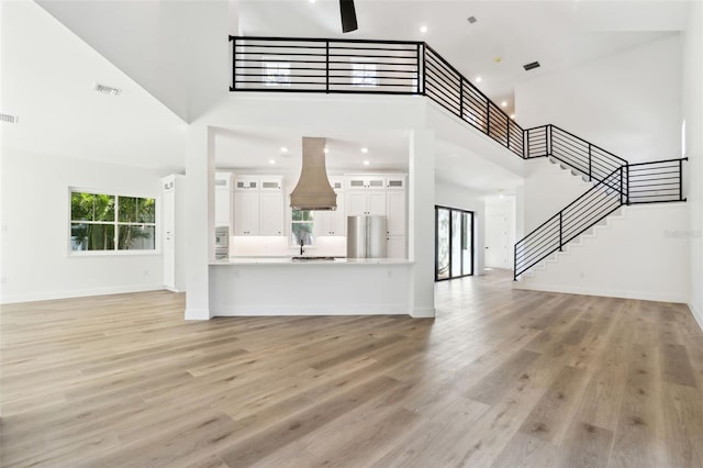 unfurnished living room featuring a towering ceiling and light hardwood / wood-style floors