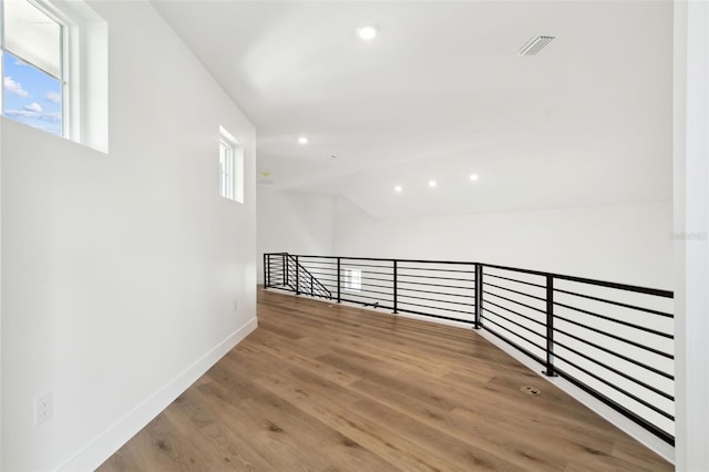 hall with a wealth of natural light and hardwood / wood-style flooring