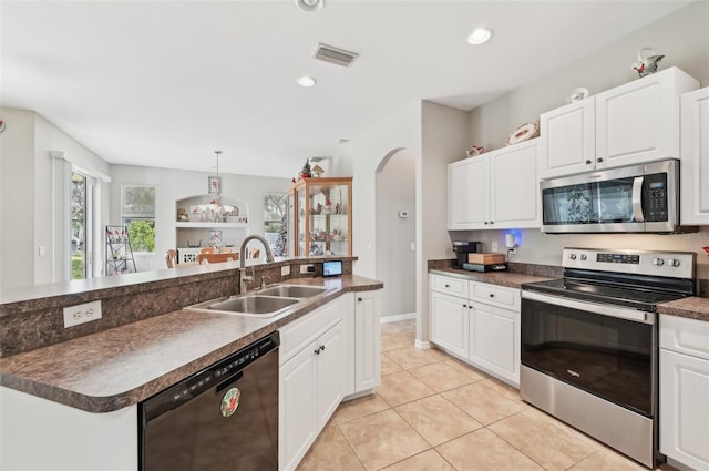 kitchen with white cabinetry, stainless steel appliances, sink, and an island with sink