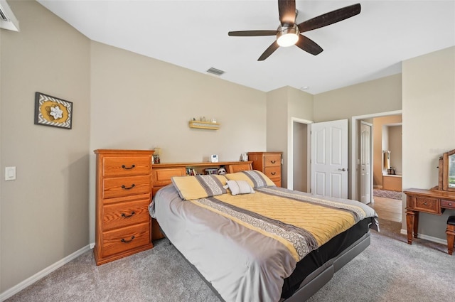 carpeted bedroom with ensuite bath and ceiling fan