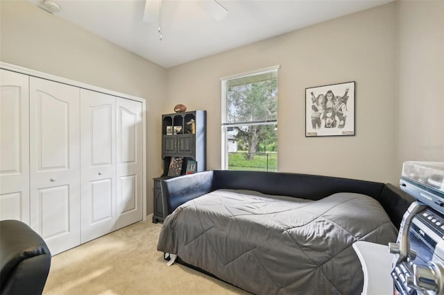 bedroom featuring light colored carpet, a closet, and ceiling fan