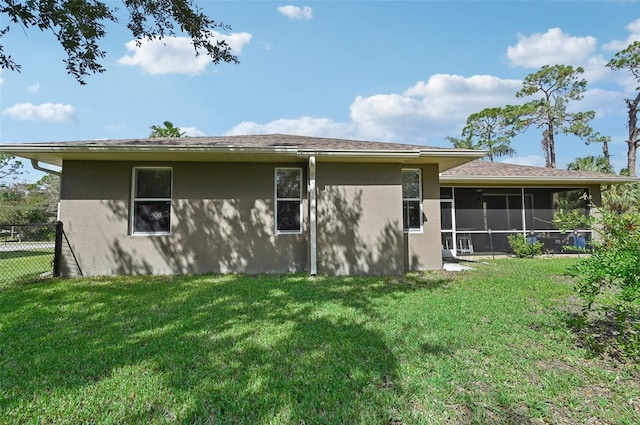 rear view of property with a lawn and a sunroom