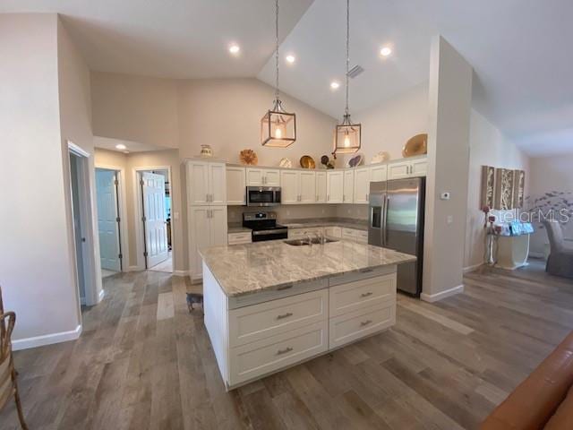 kitchen with stainless steel appliances, hardwood / wood-style floors, a center island, decorative light fixtures, and white cabinets