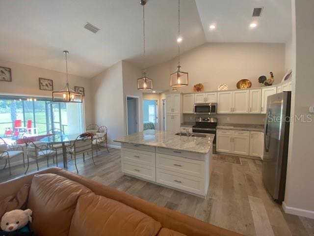 kitchen featuring pendant lighting, white cabinetry, light stone counters, and stainless steel appliances