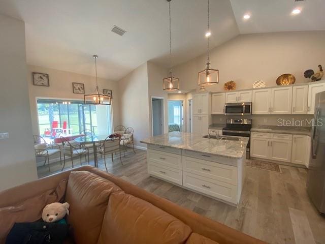 kitchen featuring white cabinetry, appliances with stainless steel finishes, lofted ceiling, and hanging light fixtures