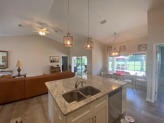 kitchen featuring an island with sink, light stone countertops, stainless steel dishwasher, pendant lighting, and sink