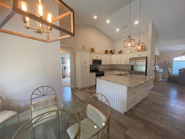 kitchen featuring light stone countertops, a center island, white cabinets, appliances with stainless steel finishes, and dark hardwood / wood-style flooring