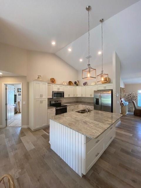 kitchen featuring a kitchen island with sink, white cabinetry, decorative light fixtures, and stainless steel appliances