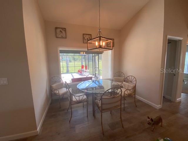 dining space with lofted ceiling, dark wood-type flooring, and a chandelier