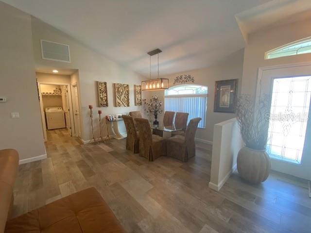 dining space with lofted ceiling, hardwood / wood-style floors, and washer / clothes dryer