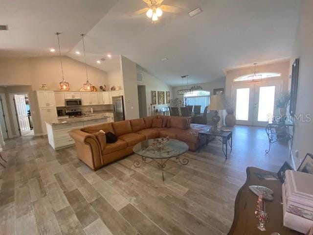 living room with french doors, light hardwood / wood-style floors, high vaulted ceiling, and ceiling fan