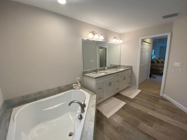 bathroom with vanity, hardwood / wood-style flooring, and a washtub