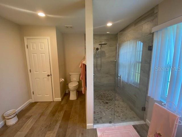 bathroom with a shower with door, toilet, and wood-type flooring