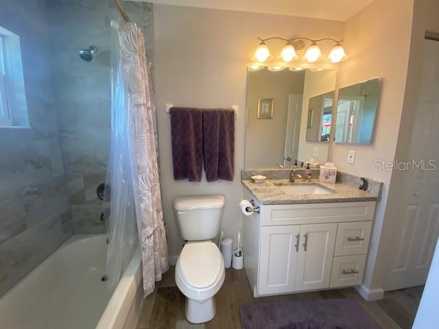 full bathroom featuring vanity, shower / tub combo with curtain, toilet, and hardwood / wood-style flooring