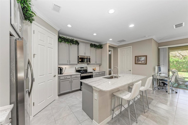 kitchen featuring light stone countertops, stainless steel appliances, a kitchen island with sink, sink, and gray cabinets