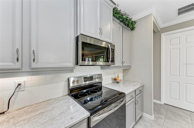 kitchen featuring light stone countertops, appliances with stainless steel finishes, backsplash, crown molding, and light tile patterned floors