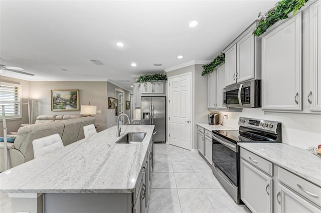 kitchen with gray cabinetry, sink, a center island with sink, appliances with stainless steel finishes, and ornamental molding