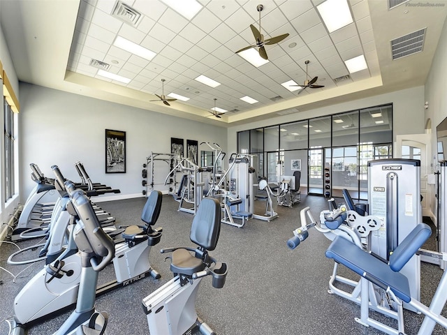 exercise room with a tray ceiling, ceiling fan, and a drop ceiling