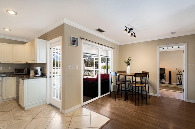 kitchen featuring dark stone countertops, light hardwood / wood-style floors, ornamental molding, and white cabinets